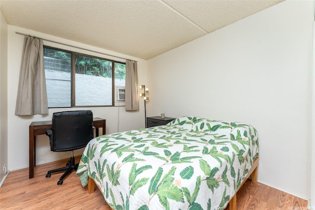 bedroom with cooling unit and wood finished floors