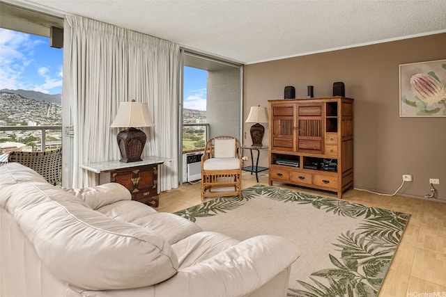living room with light tile patterned floors, ornamental molding, a wall of windows, a mountain view, and a textured ceiling