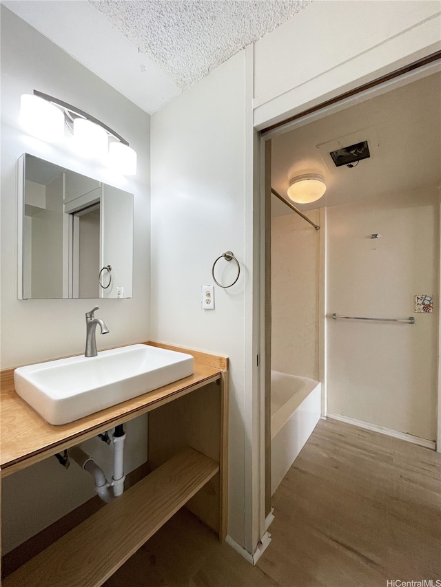 1624 Kanunu St Unit 306, Honolulu, HI 96814 - bathroom with wood finished floors, a textured ceiling, a sink, and shower / bathing tub combination