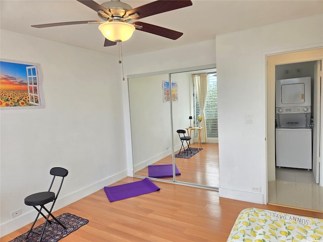1535 Pensacola St Unit 36, Honolulu, HI 96822 - workout room featuring stacked washer / drying machine, wood finished floors, a ceiling fan, and baseboards