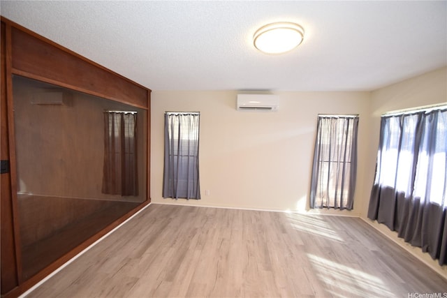 spare room with baseboards, light wood finished floors, and a wall mounted AC
