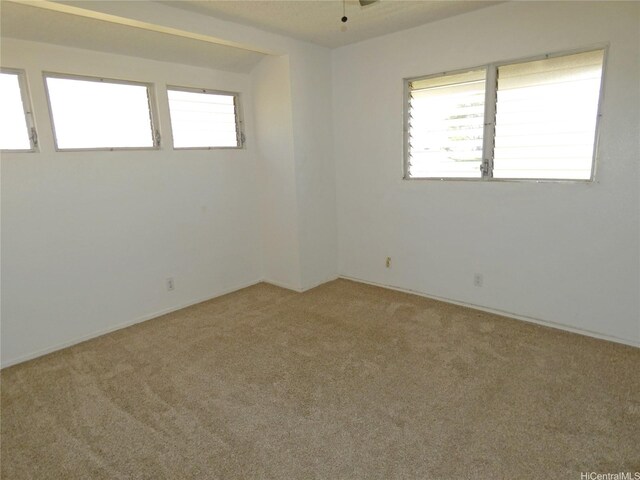 spare room with baseboards, a wealth of natural light, ceiling fan, and light colored carpet
