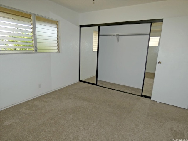 unfurnished bedroom featuring multiple windows, carpet, and a closet