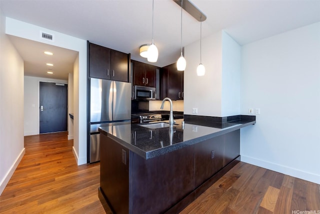 1189 Waimanu St Unit 2308, Honolulu, HI 96814 - kitchen featuring dark brown cabinetry, appliances with stainless steel finishes, a sink, a peninsula, and visible vents