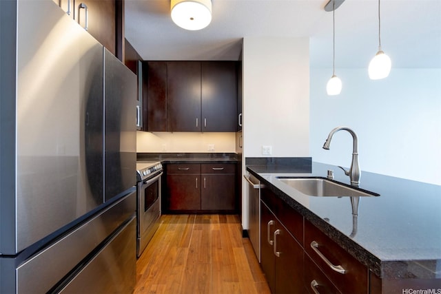 1189 Waimanu St Unit 2308, Honolulu, HI 96814 - kitchen featuring a sink, light wood-style floors, dark stone countertops, stainless steel appliances, and decorative light fixtures