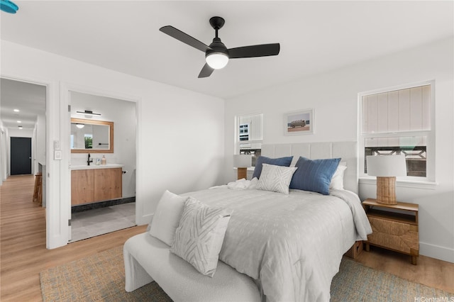 bedroom featuring baseboards, light wood-style flooring, ensuite bathroom, and ceiling fan