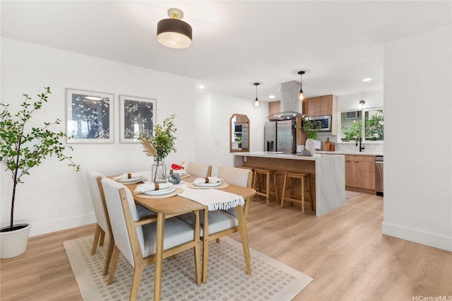 dining room with recessed lighting, baseboards, and light wood-style flooring