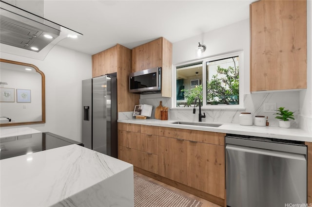 kitchen featuring appliances with stainless steel finishes, ventilation hood, a sink, decorative backsplash, and modern cabinets