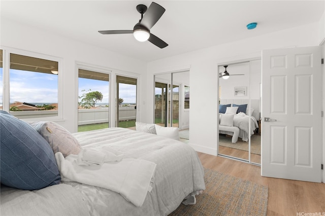 bedroom with multiple closets, ceiling fan, light wood-type flooring, and access to outside