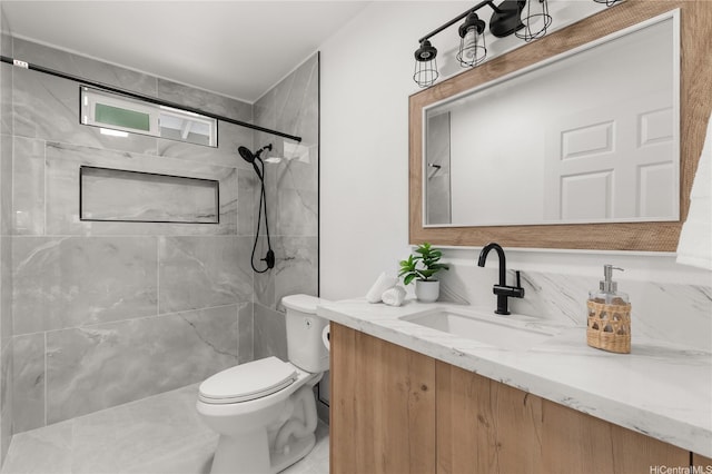 full bathroom with toilet, a tile shower, and vanity