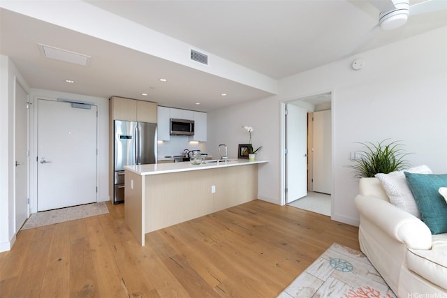 1001 Queen St Unit 1804, Honolulu, HI 96814 - kitchen featuring appliances with stainless steel finishes, a peninsula, a sink, light wood-style floors, and light countertops