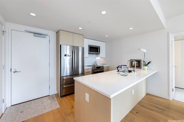 1001 Queen St Unit 1804, Honolulu, HI 96814 - kitchen featuring appliances with stainless steel finishes, light wood-style flooring, a peninsula, a sink, and recessed lighting