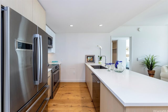 1001 Queen St Unit 1804, Honolulu, HI 96814 - kitchen featuring appliances with stainless steel finishes, a sink, a peninsula, modern cabinets, and light wood-type flooring