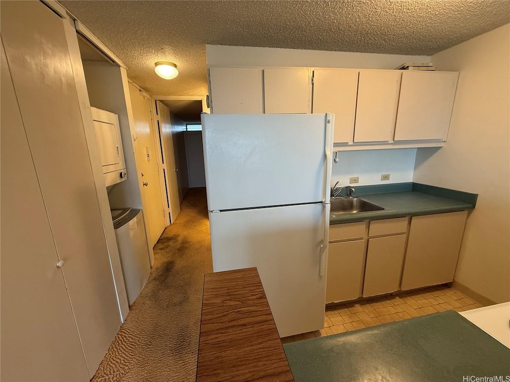 2611 Ala Wai St Unit 806, Honolulu, HI 96815 - kitchen featuring stacked washing maching and dryer, a textured ceiling, freestanding refrigerator, and a sink