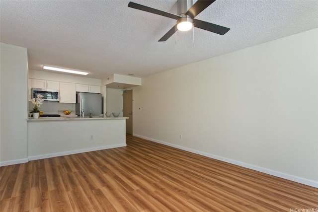 1133 Waimanu St Unit 201, Honolulu, HI 96814 - unfurnished living room featuring baseboards, a textured ceiling, ceiling fan, and wood finished floors