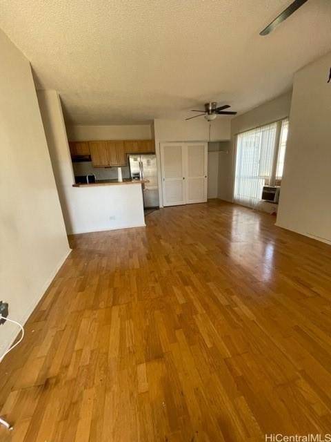 unfurnished living room featuring a ceiling fan, a textured ceiling, and wood finished floors