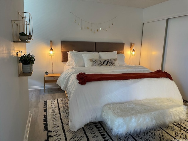 bedroom featuring wood finished floors, baseboards, and a closet