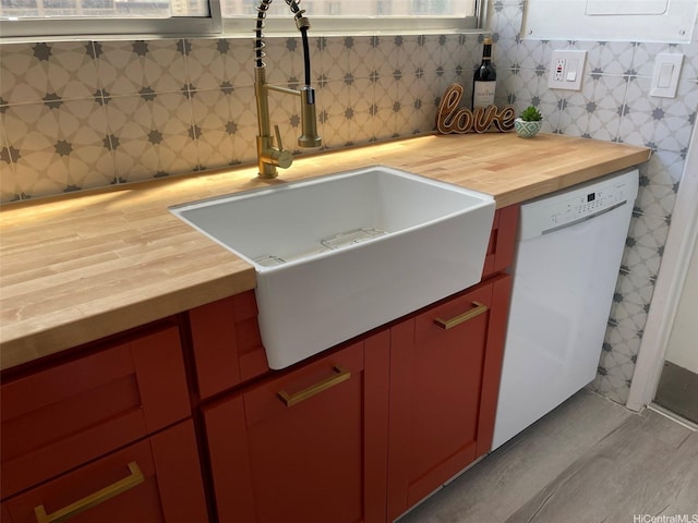 kitchen view of wood counters, red cabinets, white dishwasher, and a sink
