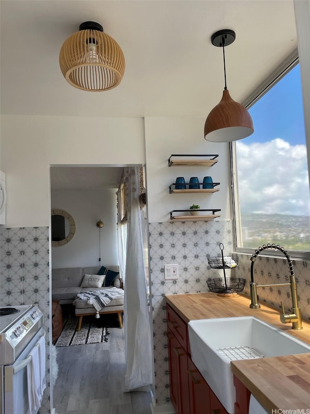 interior space featuring butcher block counters, white electric range, a sink, plenty of natural light, and tile walls
