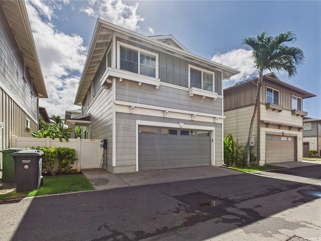 view of front of property featuring an attached garage, board and batten siding, fence, and asphalt driveway