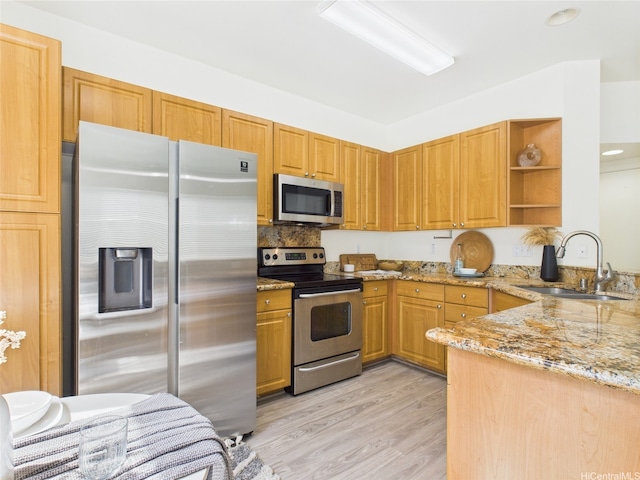 kitchen featuring stainless steel appliances, a sink, open shelves, light stone counters, and light wood-style flooring