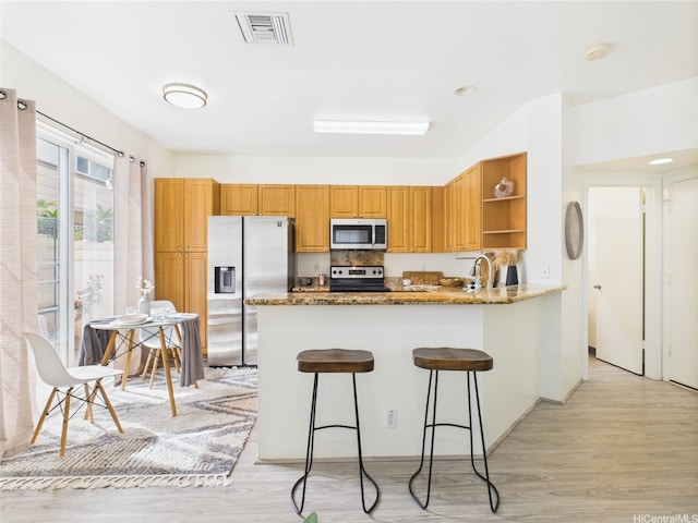 kitchen featuring stainless steel appliances, open shelves, light wood-type flooring, and a peninsula