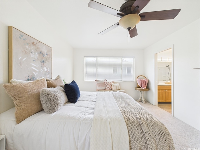 bedroom with light colored carpet, a ceiling fan, and ensuite bath