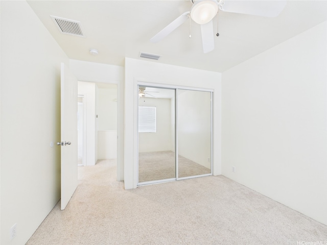 unfurnished bedroom featuring light carpet, a closet, and a ceiling fan