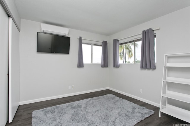 bedroom featuring baseboards, a wall mounted air conditioner, and dark wood-style floors