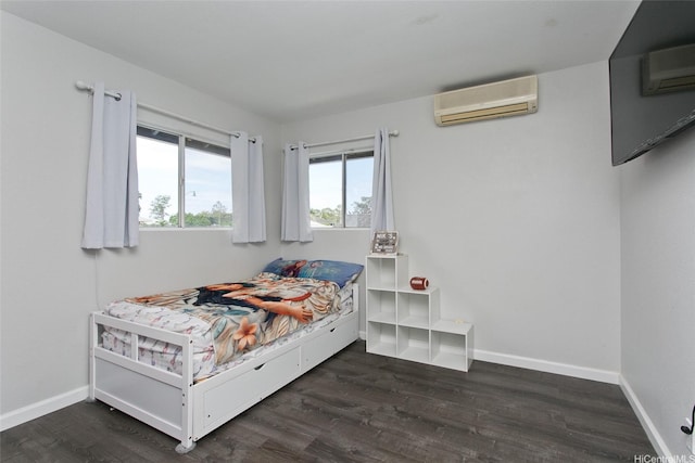 bedroom with baseboards, dark wood-style floors, and a wall unit AC