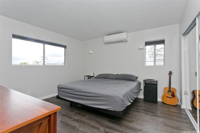 bedroom with baseboards, a wall mounted AC, and dark wood-type flooring