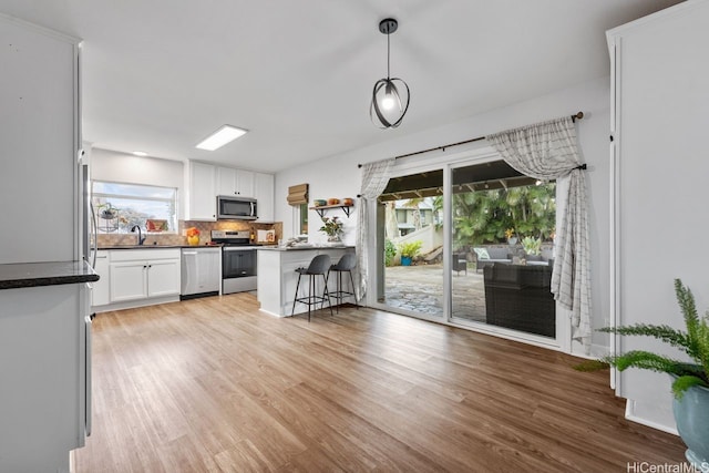 92-1288 Kikaha St Unit 78, Kapolei, HI 96707 - interior space featuring decorative backsplash, appliances with stainless steel finishes, a sink, white cabinets, and light wood finished floors