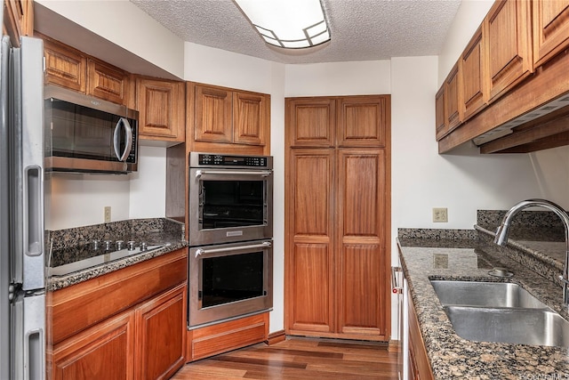 581 Kamoku St Unit 1008, Honolulu, HI 96826 - kitchen featuring brown cabinetry, a sink, a textured ceiling, and appliances with stainless steel finishes