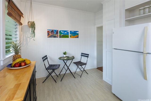 dining area featuring ornamental molding and light wood finished floors