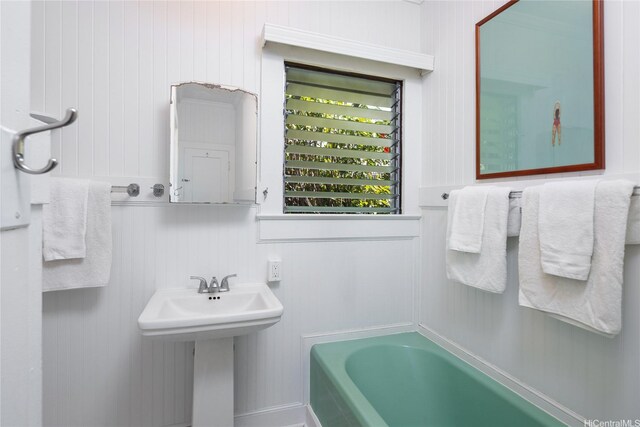 bathroom featuring a sink, a bathing tub, and a decorative wall