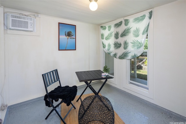 office space featuring baseboards, an AC wall unit, and speckled floor