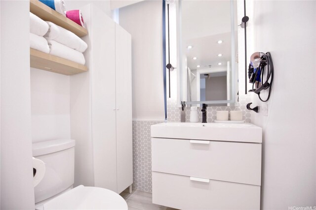 229 Paoakalani Ave Unit 1513, Honolulu, HI 96815 - half bathroom with vanity, wainscoting, toilet, and tile walls
