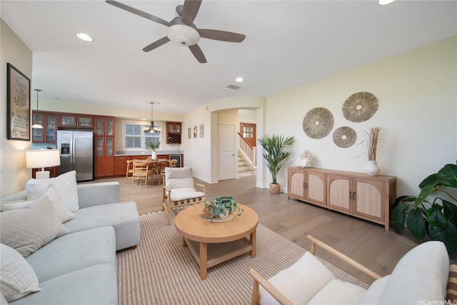 91-1243 Kuanoo St, Ewa Beach, HI 96706 - living room with stairs, a chandelier, light wood-style flooring, arched walkways, and a ceiling fan