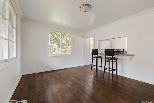 dining space featuring dark wood-style flooring, crown molding, and baseboards