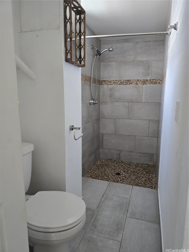 full bath with toilet, tiled shower, and tile patterned floors