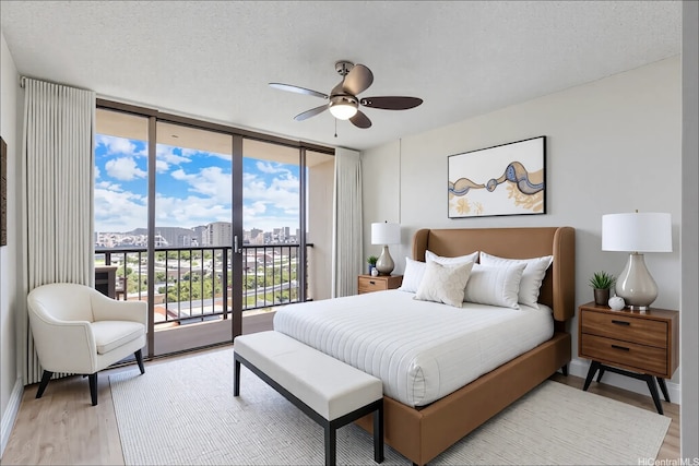 1201 Wilder Ave Unit 2701, Honolulu, HI 96822 - bedroom with access to exterior, light wood-style flooring, floor to ceiling windows, a city view, and a textured ceiling
