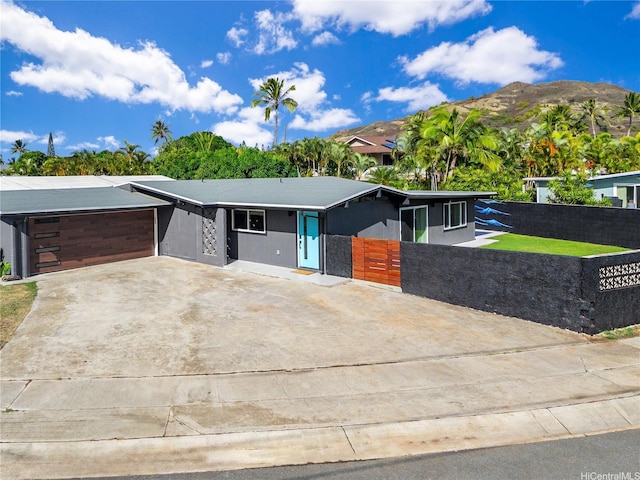 view of front facade featuring an attached garage, fence private yard, and driveway