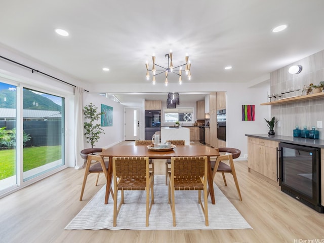 dining room with light wood-type flooring, recessed lighting, wine cooler, and an inviting chandelier