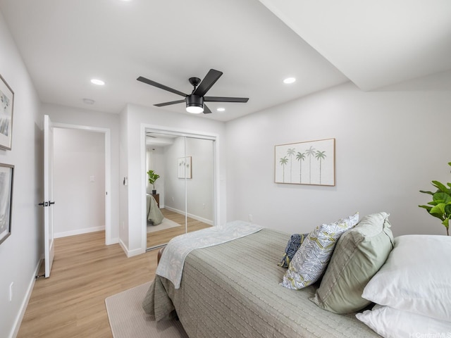 bedroom with recessed lighting, light wood-style flooring, baseboards, and a closet