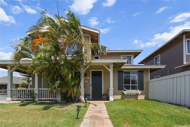 view of front of home featuring covered porch, fence, and a front yard