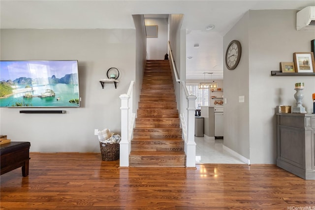 staircase with wood finished floors and a wall mounted air conditioner