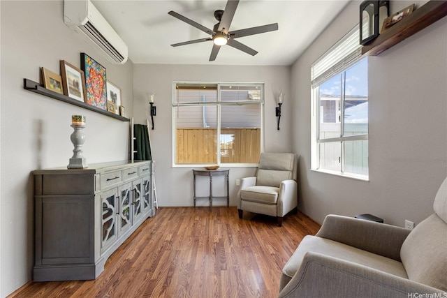 living area featuring an AC wall unit, a ceiling fan, and wood finished floors