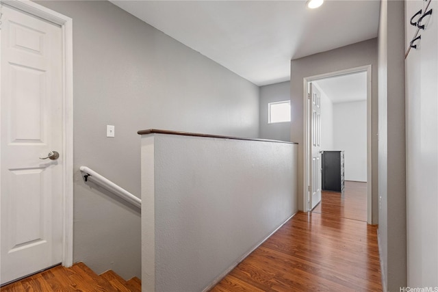 hall with wood finished floors and an upstairs landing
