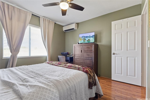 bedroom with a ceiling fan, light wood-style flooring, and a wall mounted air conditioner