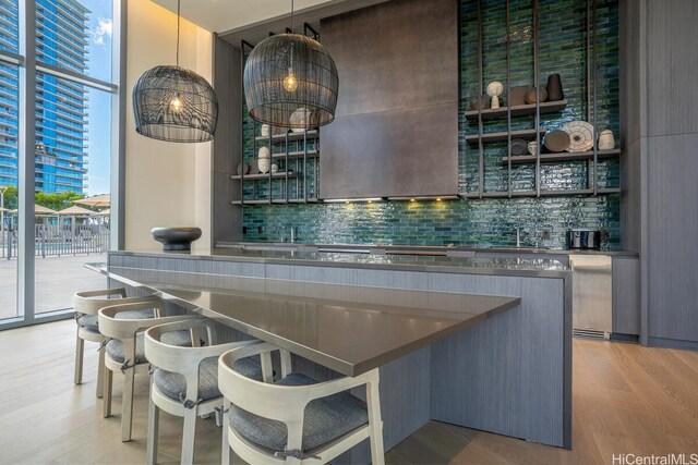 1000 Auahi St Unit 1404, Honolulu, HI 96814 - bar featuring a sink, wet bar, light wood-type flooring, backsplash, and expansive windows
